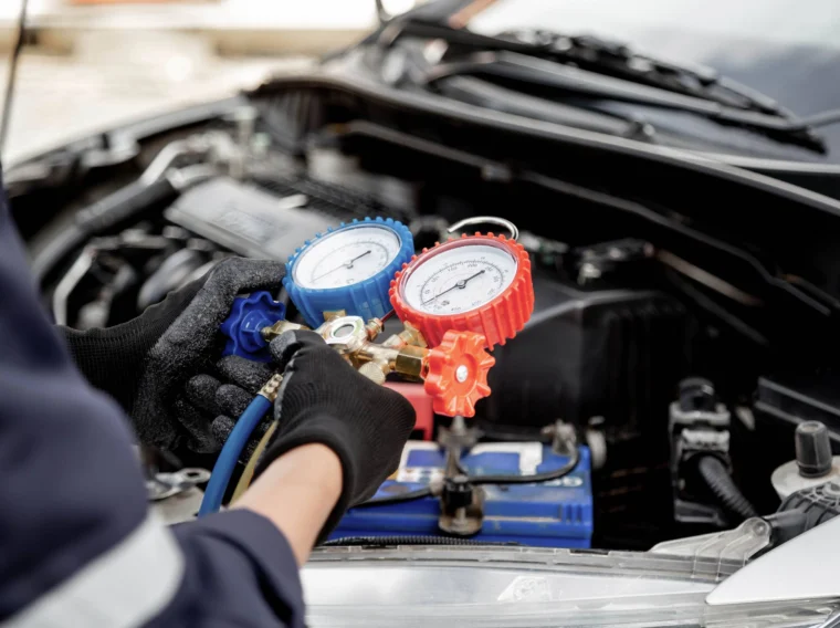 Close up hand of auto mechanic using measuring manifold gauge check the refrigerant and filling car air conditioner for fix.