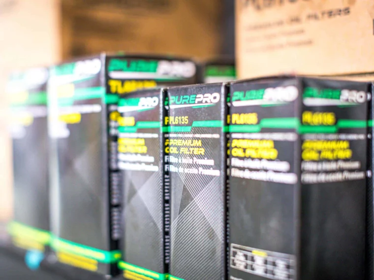Rows of PUREPRO oil filter boxes are displayed on a shelf, with product labels and codes visible on the front—ideal for anyone looking for reliable Filter Services.