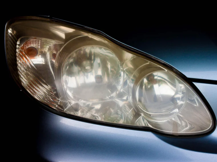 Close-up view of a car's headlight on a metallic blue vehicle, highlighting the precise design of the headlamp cover and surrounding bodywork—perfect inspiration for automotive lighting services.