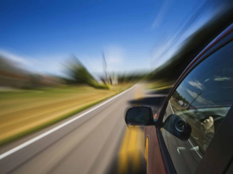 View from a moving car on a rural road, with motion blur effect emphasizing speed and blue sky above—perfect scenery for those seeking top-notch alignment services to keep drives smooth and steady.