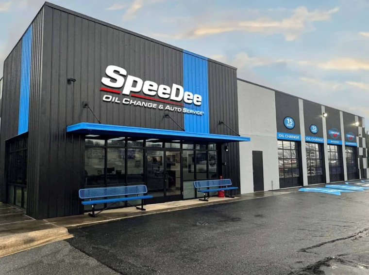 Exterior view of a SpeeDee oil change and auto service location with four bay doors and a clean entry with two benches