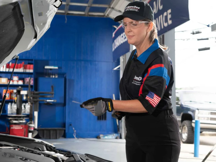 A mechanic in uniform with safety glasses and gloves inspects a car engine in an auto service garage, ensuring top-quality tune up services for optimal vehicle performance.